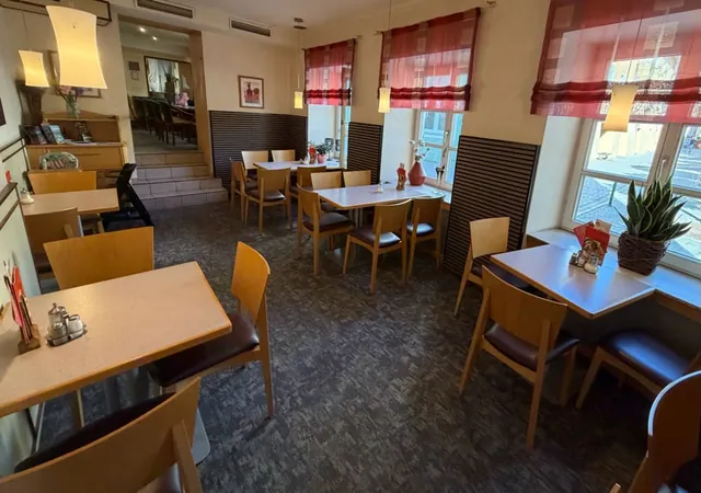 Our dining room with light wooden chairs and red curtains at the windows